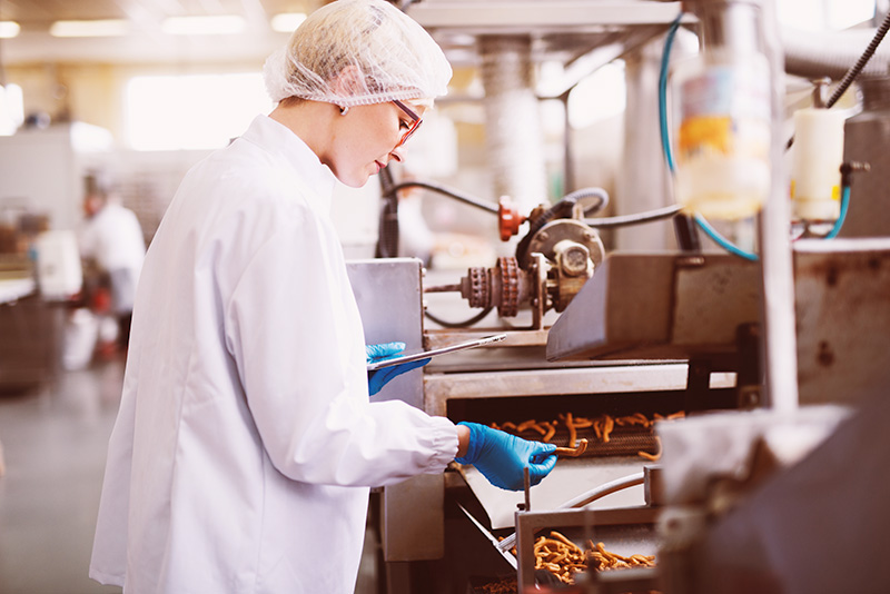 Young female worker in sterile clothes is taking a sample of sal