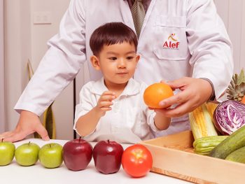 Healthy and nutrition concept. Kid learning about nutrition with doctor to choose eating fresh fruits and vegetables.Young asian boy holding orange.